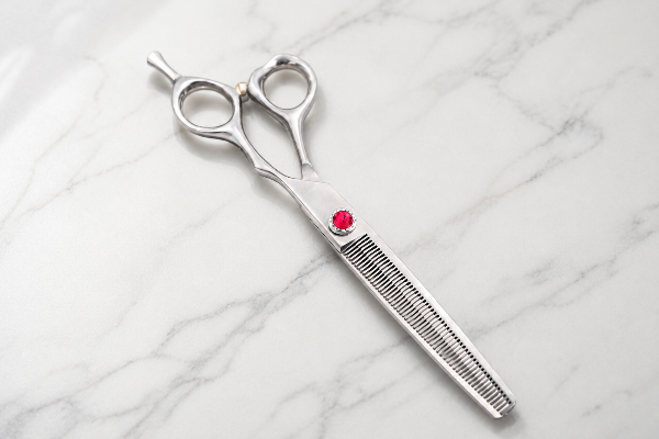 Thinning texturizing shear with red tension screw on a marble surface